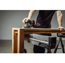 Ein Mann schleift Holz mit einem Metabo Exzenterschleifer auf einer Metabo MAB 82 Montagebank.