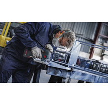 Ein Handwerker schneidet Metall mit einer Stichsäge in einer Werkstatt.