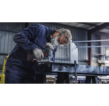 Handwerker mit Schutzmaske und Schutzbrille sägt ein Werkstück mit einer Stichsäge.