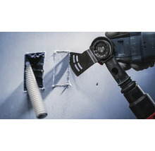 Oszillierendes Elektrowerkzeug schneidet eine quadratische Form in eine Wand neben einer Öffnung mit einem Kabel