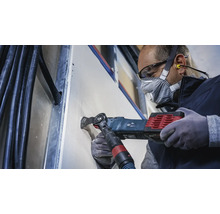 Handwerker schneidet mit einem Multifunktionswerkzeug eine Öffnung in eine Gipskartonwand.