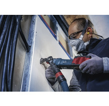 Handwerker schneidet mit einem Multifunktionswerkzeug ein Loch in eine Trockenbauwand