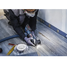 Handwerker verwendet Multifunktionswerkzeug auf Laminatboden für Renovierungsarbeiten.