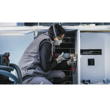 Eine Handwerkerin arbeitet mit einem Multifunktionswerkzeug an einem Waschtisch im Badezimmer.