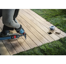 Handwerker bearbeitet eine Holzterrasse mit einem Multifunktionswerkzeug