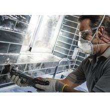 Handwerker arbeitet mit einem Multifunktionswerkzeug an Fliesen in einem Badezimmer