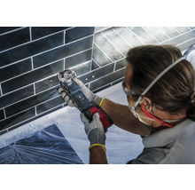 Handwerker bei der Fliesenfugenbearbeitung mit einem Multifunktionswerkzeug