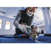 Handwerker schneidet Teppich mit einem Elektrowerkzeug