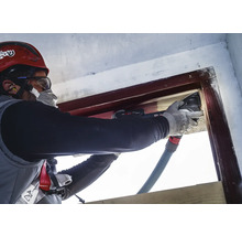 Handwerker renoviert Fensterrahmen mit einem Multifunktionswerkzeug