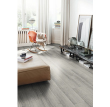 Wohnzimmer mit grauem Laminatboden, Sitzhocker und Schaukelstuhl.