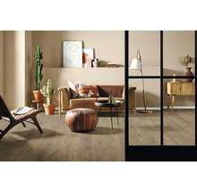 Wohnzimmer mit Sofa, Sessel, Tisch, Stehlampe, Kommode, Dekoration und Zimmerpflanzen auf Holzboden.