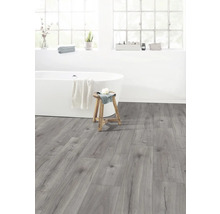 Helles Badezimmer mit Badewanne, Hocker und grauem Laminatboden.