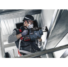 Ein Arbeiter bohrt mit einem Bohrhammer in eine Wand.