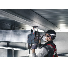 Handwerker bohrt mit einem Bohrhammer ein Loch in eine Betondecke.