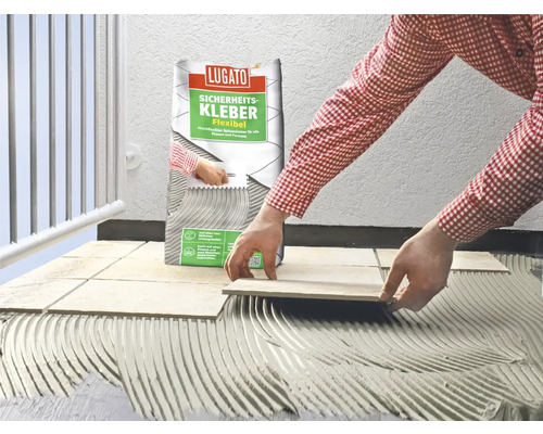 Eine Person verlegt Fliesen mit Fliesenkleber der Marke Lugato.