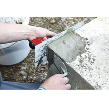 Eine Person glättet Beton mit einer Glättkelle.