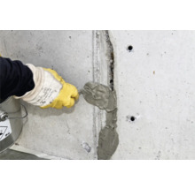 Handwerker füllt Riss in einer Betonwand mit Spachtelmasse