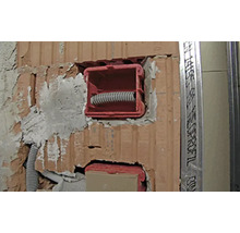 Installation einer Gerätedose in einer Ziegelwand mit Leerrohr.