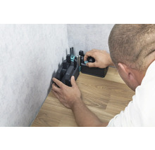 Eine Gehrungslade wird an einer Ecke auf einem Holzboden befestigt.