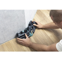 Person verwendet eine Schneidlade zum Schneiden von Sockelleisten.