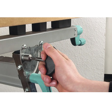 Eine Person befestigt einen Schrauben mit einem Schraubendreher an einem Metallbettrahmen.