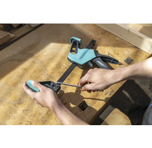 Eine Person justiert eine Einhandzwinge mit einem Innensechskantschlüssel auf einer Werkbank.