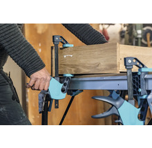Handwerker fixiert Holz mit einer Einhandzwinge auf einem Werktisch