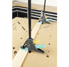 Zwei Wolfcraft Einhandzwingen fixieren ein Werkstück auf einer Werkbank.