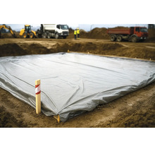 Abdeckplane auf einer Baustelle mit Baumaschinen im Hintergrund.