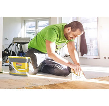 Ein Mann verlegt Parkett mit Soudal Parkettklebstoff