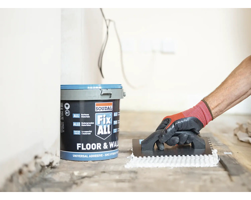 Produktbild 6 (groß) Ein Eimer Soudal Fix ALL Klebstoff und eine Person, die Klebstoff mit einer Kelle aufträgt.