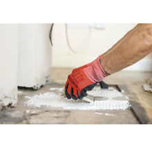 Fliesenleger trägt Klebstoff auf Fliesen auf