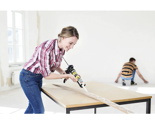 Produktbild 2 (groß) Frau trägt Klebstoff mit einer Pistole auf Holzleiste auf einem Tisch auf