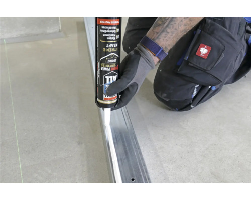 Handwerker trägt Klebstoff auf Metallprofil auf, Fix All Extreme Power Kleber