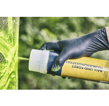 Eine Person mit Handschuhen verwendet Markierungsspray für Bau und Forst.