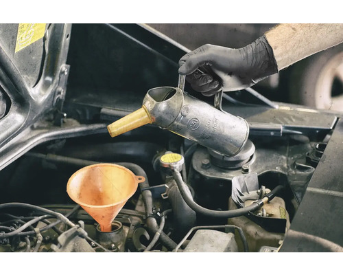Motoröl wird mit Trichter und Ölkännchen nachgefüllt