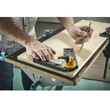 Eine Person benutzt eine Anreißlehre und einen Bleistift auf einem Holzbrett.