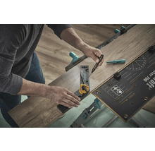 Eine Person benutzt eine Werkbank, einen Winkel und einen Stift, um ein Laminatstück zu bearbeiten.