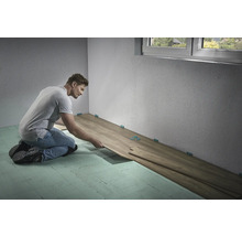 Mann verlegt Laminatboden im Innenraum mit Abstandshaltern