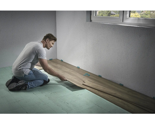 Mann verlegt Laminatboden im Innenraum mit Abstandshaltern