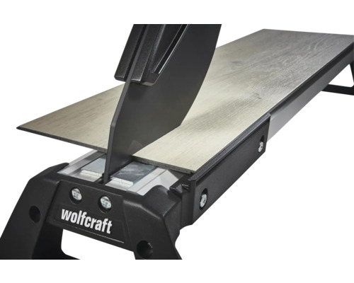 Wolfcraft Laminatschneider schneidet eine Laminatdiele mit Holzstruktur. Detailansicht der Schneidevorrichtung.