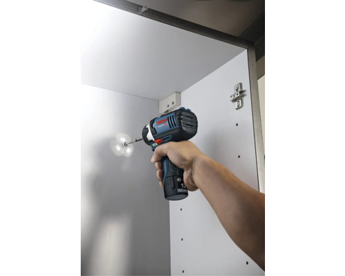 Bosch Akku-Drehschlagschrauber beim Einschrauben einer Schraube in einen weißen Schrank.