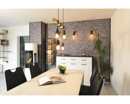 Modernes Esszimmer mit Industrial-Pendelleuchte aus Holz und Metall, Wand in Steinoptik, weißem Sideboard und Kaminofen.
