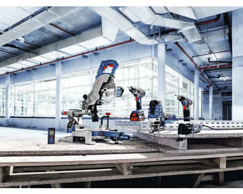 Auswahl an Bosch Professional Elektrowerkzeugen wie Kapp- und Gehrungssäge, Akkuschrauber, Stichsäge und Laser-Entfernungsmesser in einer hellen Industriehalle.