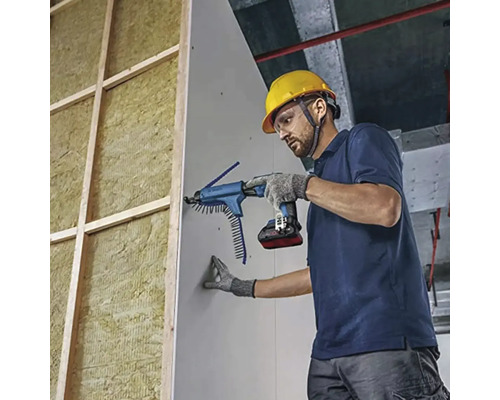 Handwerker mit Schutzhelm und Akku-Trockenbauschrauber mit Magazinvorsatz befestigt Gipskartonplatte an Holzständerwand mit Dämmung.