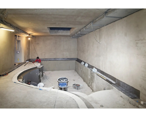 Baustelle eines Innenpools mit Arbeitern, die Abdichtungsarbeiten an den Betonwänden durchführen.