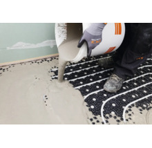 Handwerker gießt Ausgleichsmasse auf eine Fußbodenheizung mit Noppenplatte.