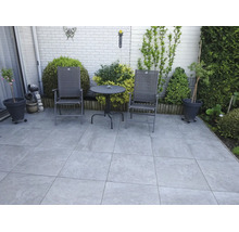 Eine Terrasse mit grossformatigen quadratischen Bodenplatten und einer Sitzgruppe bestehend aus zwei Stühlen und einem runden Gartentisch.