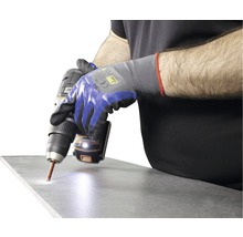 Eine Person bohrt mit einer Bohrmaschine ein Loch in eine Fliese.