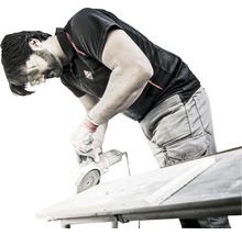 Mann schneidet Fliese mit Winkelschleifer